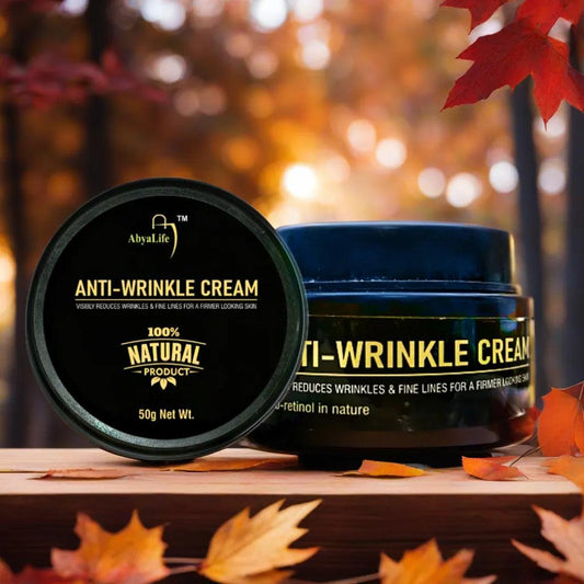 Two jars of anti-wrinkle cream, one labeled "AbyaLife ATM Anti-Wrinkle Cream" and the other labeled "AbyaLife I-Wrinkle Cream," sit side-by-side on a wooden table with blurred green leaves in the background.